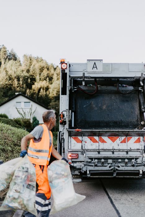 Ein Müllwerker wirft Gelbe Säcke in einen Müllwagen